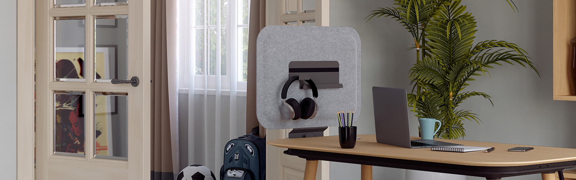 Ein modernes Home-Office-Setup mit einem Schreibtisch aus hellem Holz, einem Laptop, einem Notebook und einem akustischen Schreibtischschirm aus grauem Filz. Der Bildschirm verfügt über ein eingebautes Regal mit Kopfhörern und befindet sich in einem