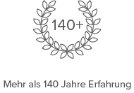 Ein minimalistisches grafisches Symbol mit einem Lorbeerkranz, der den Text 140+ umgibt und über 140 Jahre Berufserfahrung in der Möbelindustrie symbolisiert, präsentiert in einem klaren, professionellen dunkelgrauen Design auf weißem Hintergrund.