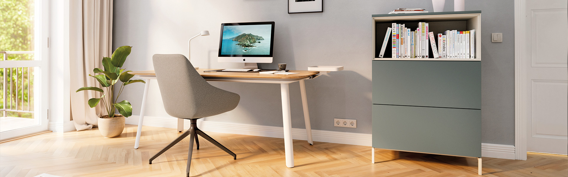 Eine moderne Heimbüroeinrichtung mit einem Holzschreibtisch mit weißen Beinen, einem grau gepolsterten Drehstuhl und einem passenden salbeigrünen Aufbewahrungsschrank mit offenem Bücherregal, alles auf einem hellen Holzboden mit Fischgrätenmuster in